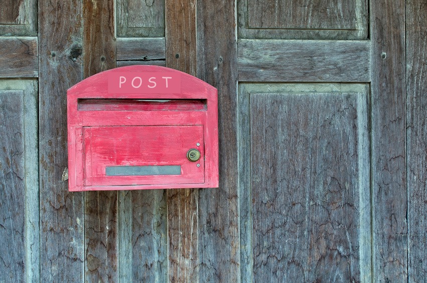 Red wooden mail box on wooden wall.